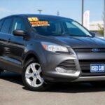 Ciemnoszary Ford Escape z tablicą Used Car zaparkowany na placu dealerskim