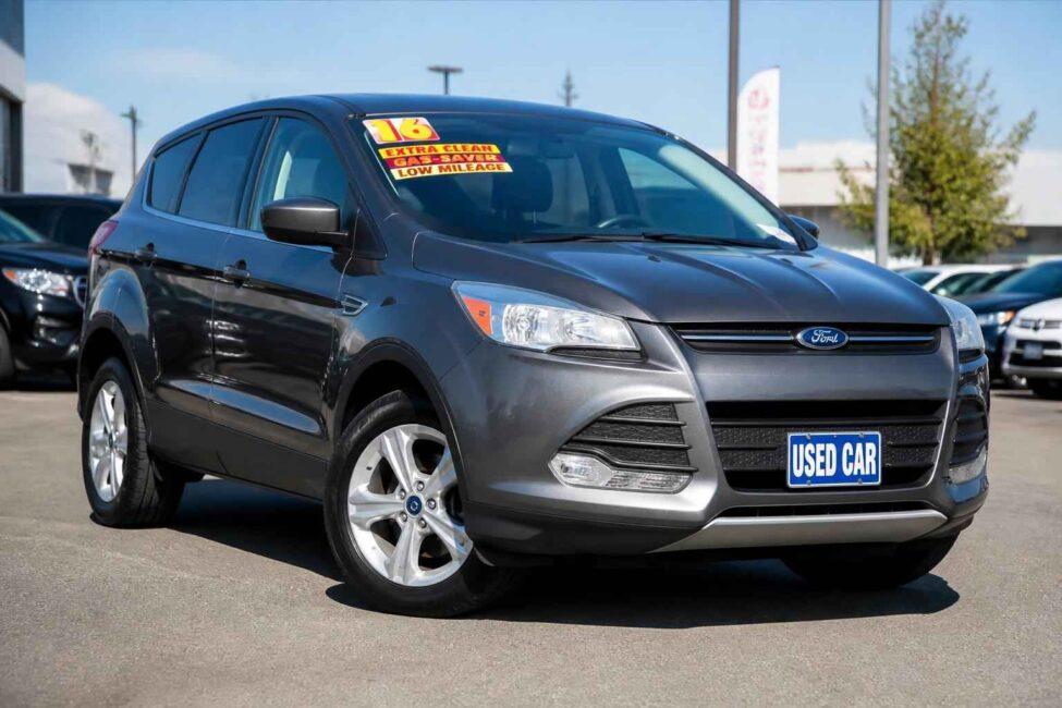 Ciemnoszary Ford Escape z tablicą Used Car zaparkowany na placu dealerskim